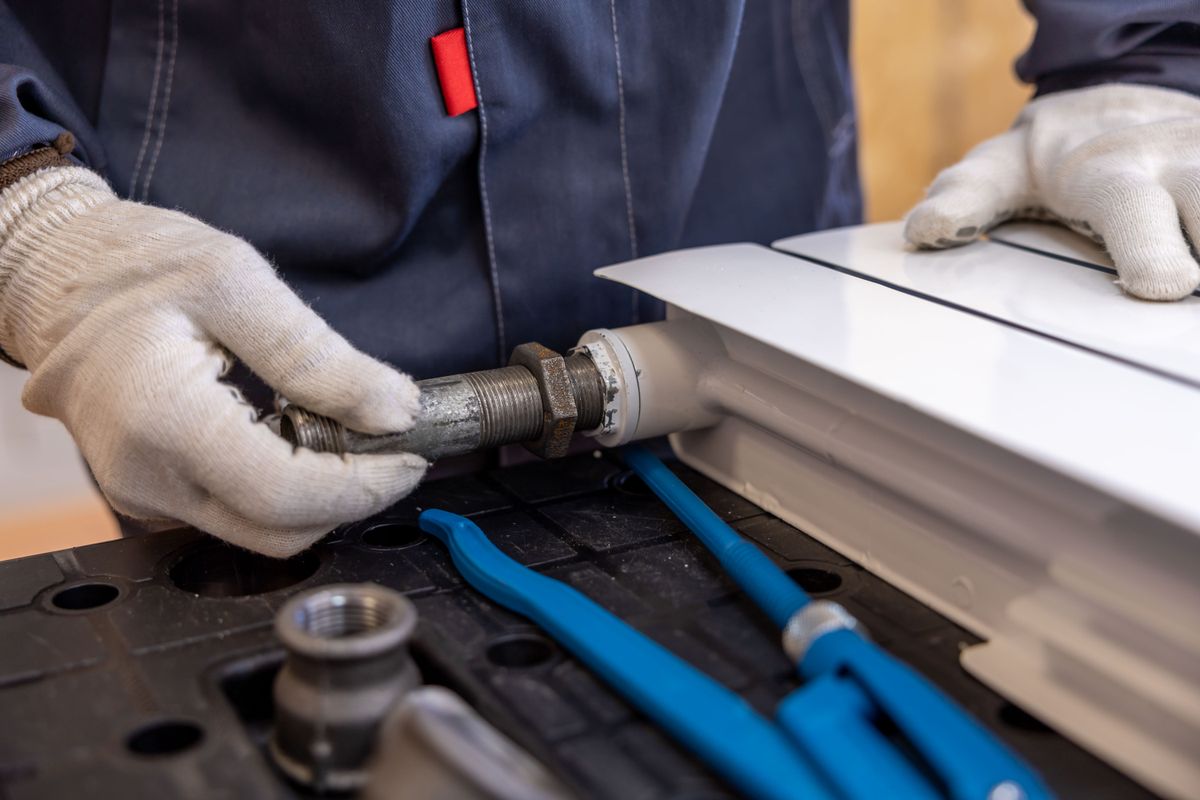 Technicien raccordant un radiateur à son réseau de chauffage